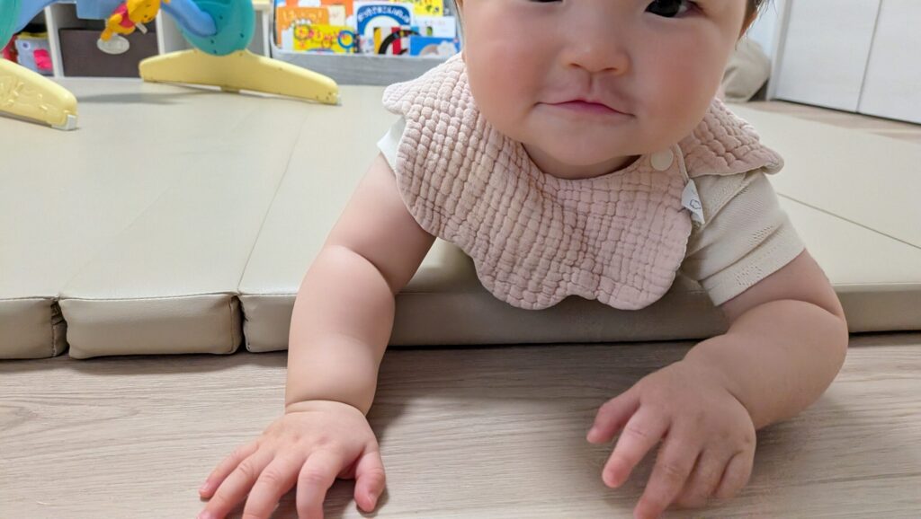 赤ちゃんがプレイマットの段差に手をついて上ろうとしている様子